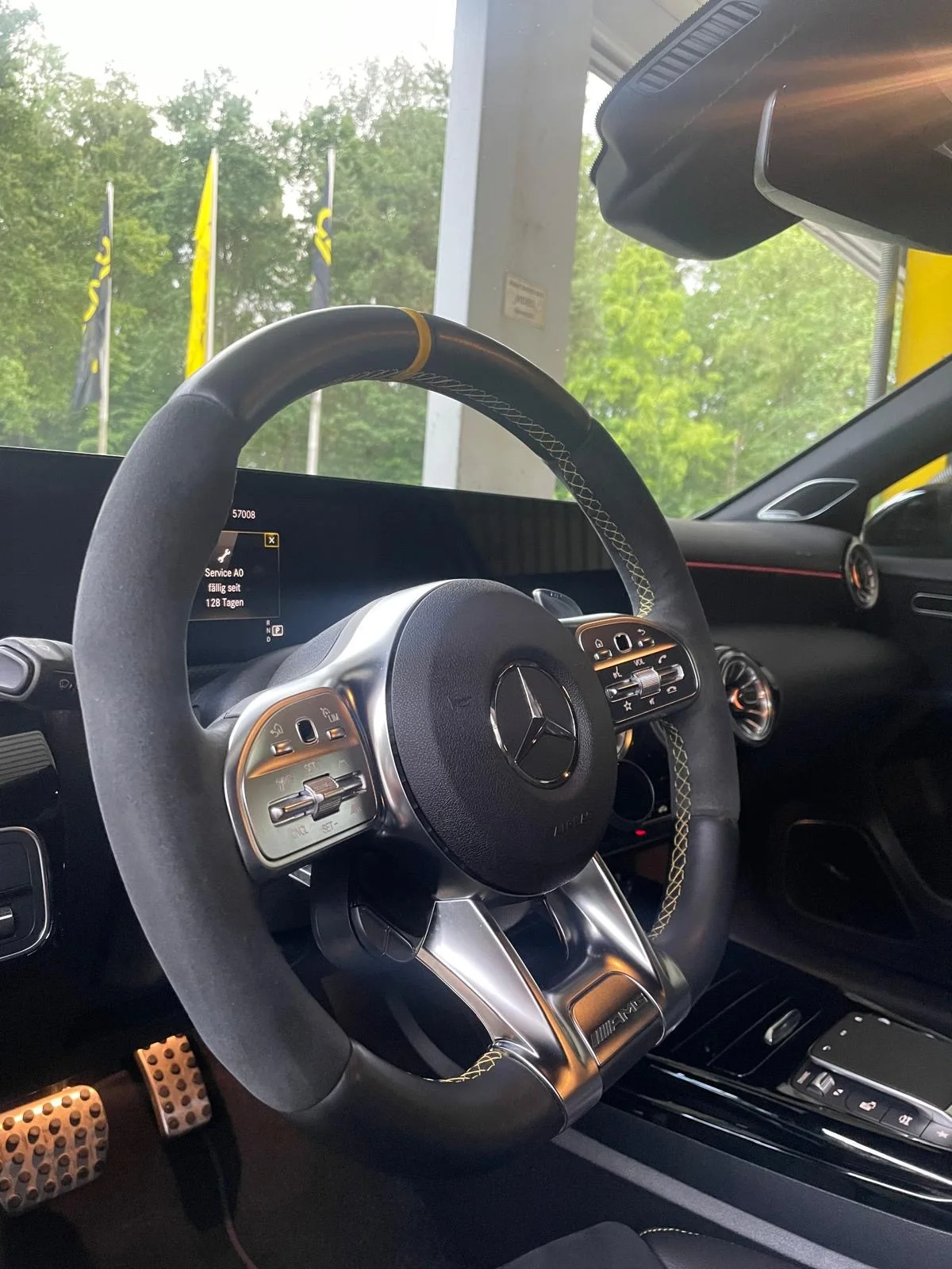 Nahaufnahme eines Mercedes-Benz Lenkrads mit gelben Nähten und Blick auf die Mittelkonsole