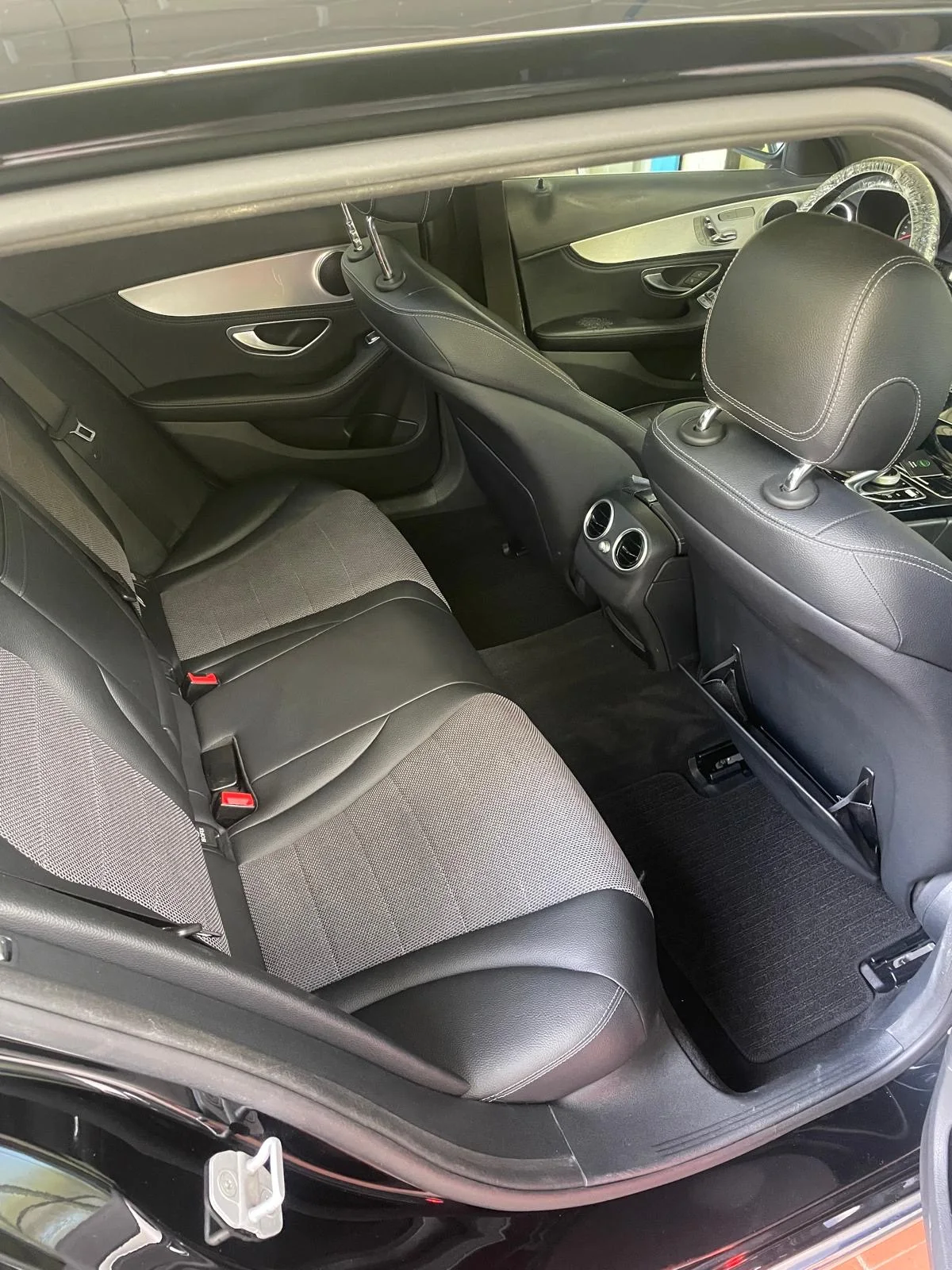 Dunkle Rückbank und hinterer Fußraum eines Mercedes-Benz mit Lüftungsdüsen zwischen den Vordersitzen