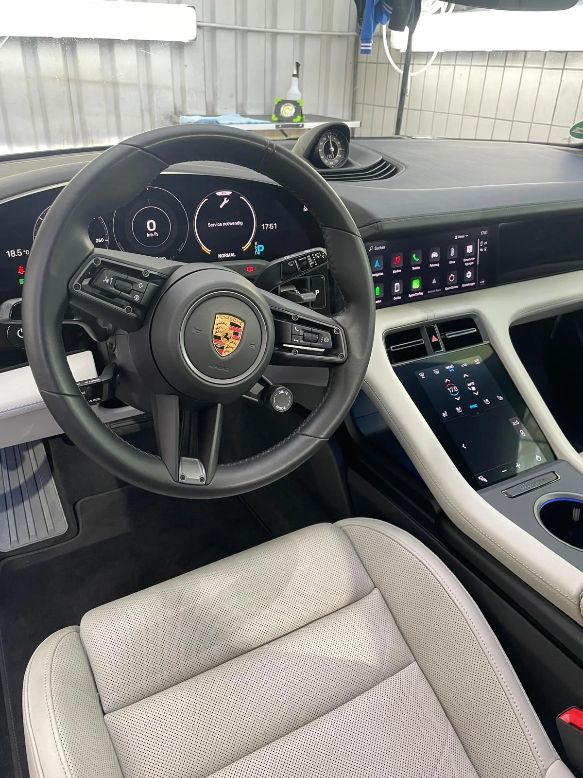 Porsche-Innenraum mit hellem Ledersitz, Lenkrad, digitalen Anzeigen und Mittelkonsole