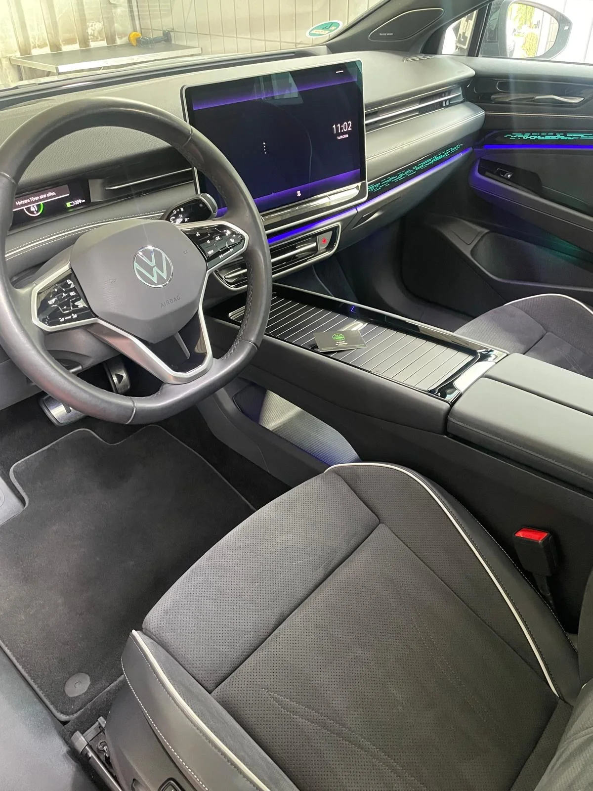 Volkswagen-Innenraum mit grauen Sitzen, großem Display und farbiger Ambientebeleuchtung